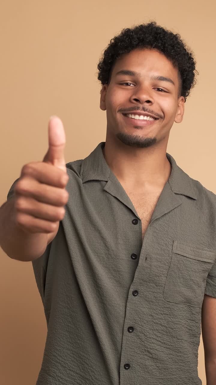 Uomo sorridente che fa il gesto del pollice in su e annuisce per mostrare approvazione.
