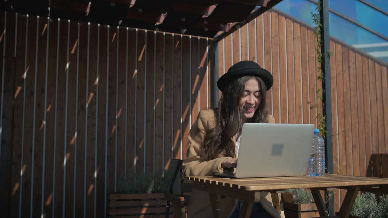 mujer trabajando en una computadora portátil al aire libre en una cafetería