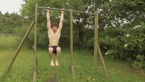 fit young man performs hanging tucked need raise isometric hold