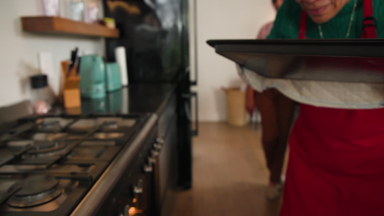 Baking Christmas cookies at home, hands carefully removing tray from oven, copy space