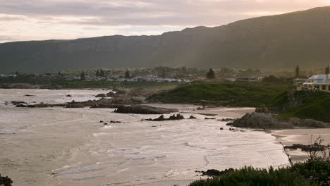 una escena tranquila de olas que corren sobre la playa de voëlklip al atardecer en hermanus