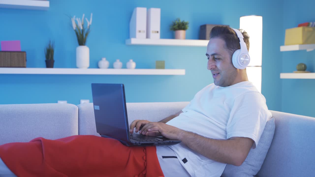 hombre bailando mientras está acostado y usando computadora portátil.