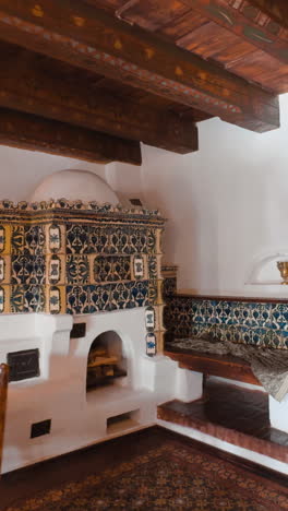room with a large fireplace with tiled fasade and lots of wooden elements and furniture. interior of bran castle, romania. vertical video