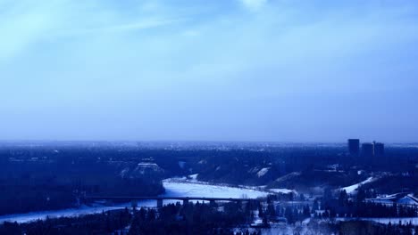 4k-Time-Lapse-winter-Groat-Road-NW-Bridge-over-snow-iced-covered-North-Saskatchewan-River-clouds-moving-at-forty-five-degrees-siluotte-cityscape-skyline-in-blue-gradations-with-lotsa-steam-clouds