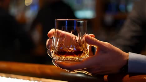 whiskey glass in hands at a bar