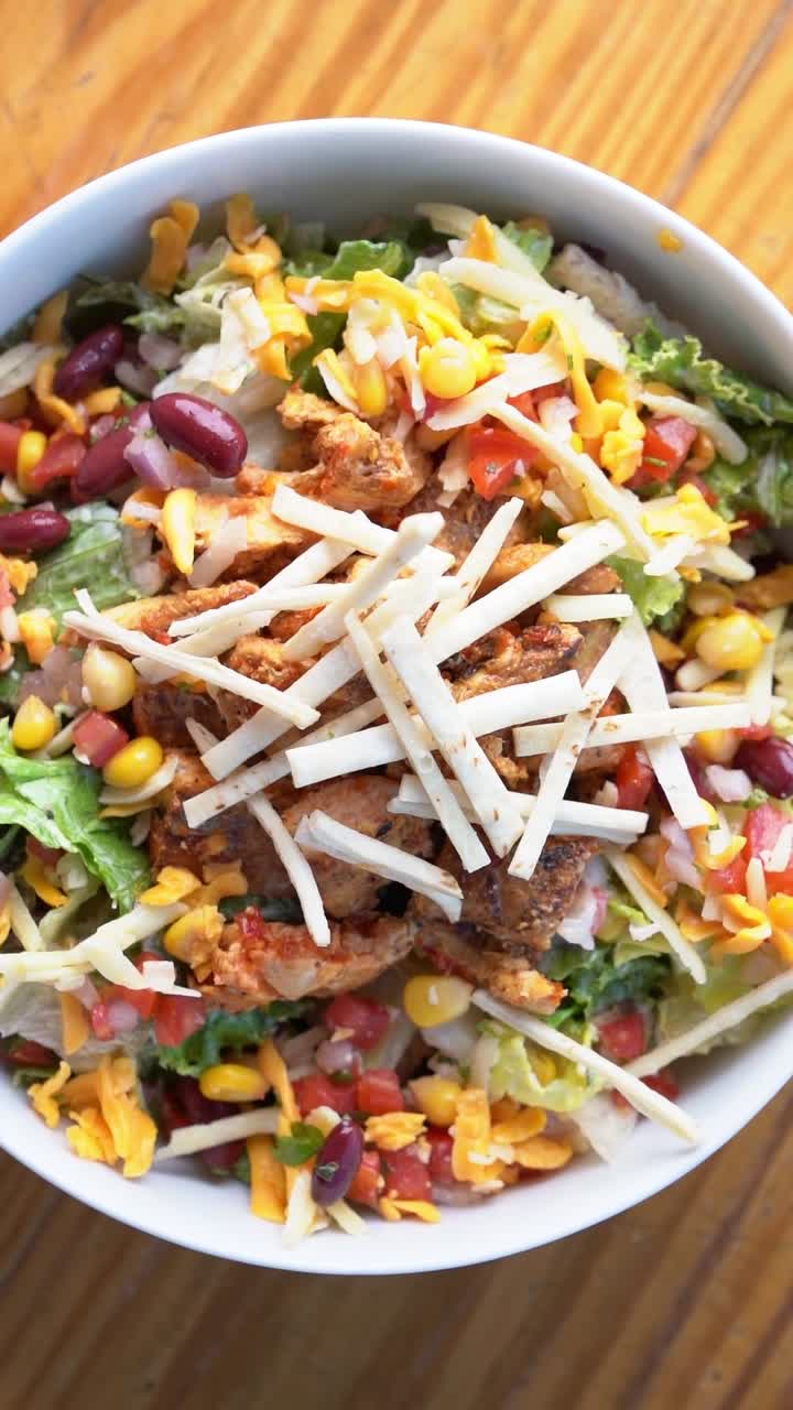 A colorful chicken salad topped with cheese, close up shot