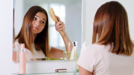 Concepto-De-Belleza-Y-Gente-Adolescente-Mirando-Al-Espejo-Y-Cepillándose-El-Cabello-Con-Peine-En-El-Baño-De-Casa