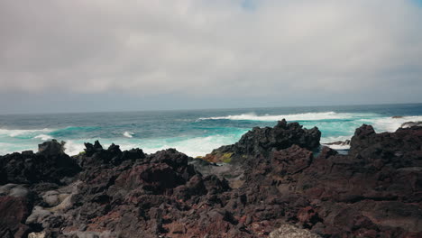 Slow-motion-shot-of-rough-ocean-waves-crushing-against-the-volcanic-rocky-coastline