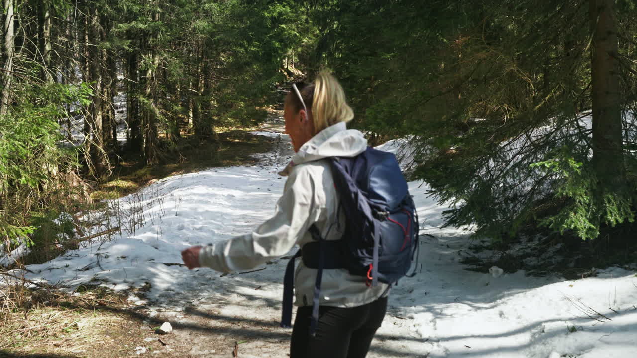 Girl mountaineer smiling at the camera while taking a walk in a snowy forest.