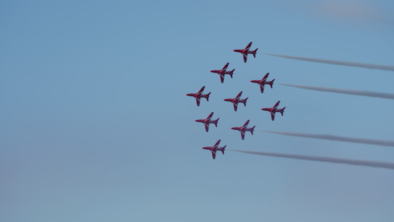 Red Jet Planes Flying in Formation with Smoke Trails Across Blue Sky