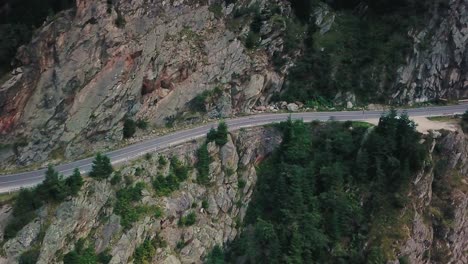 Drone-shot-of-a-mountain-road-next-to-a-cliff