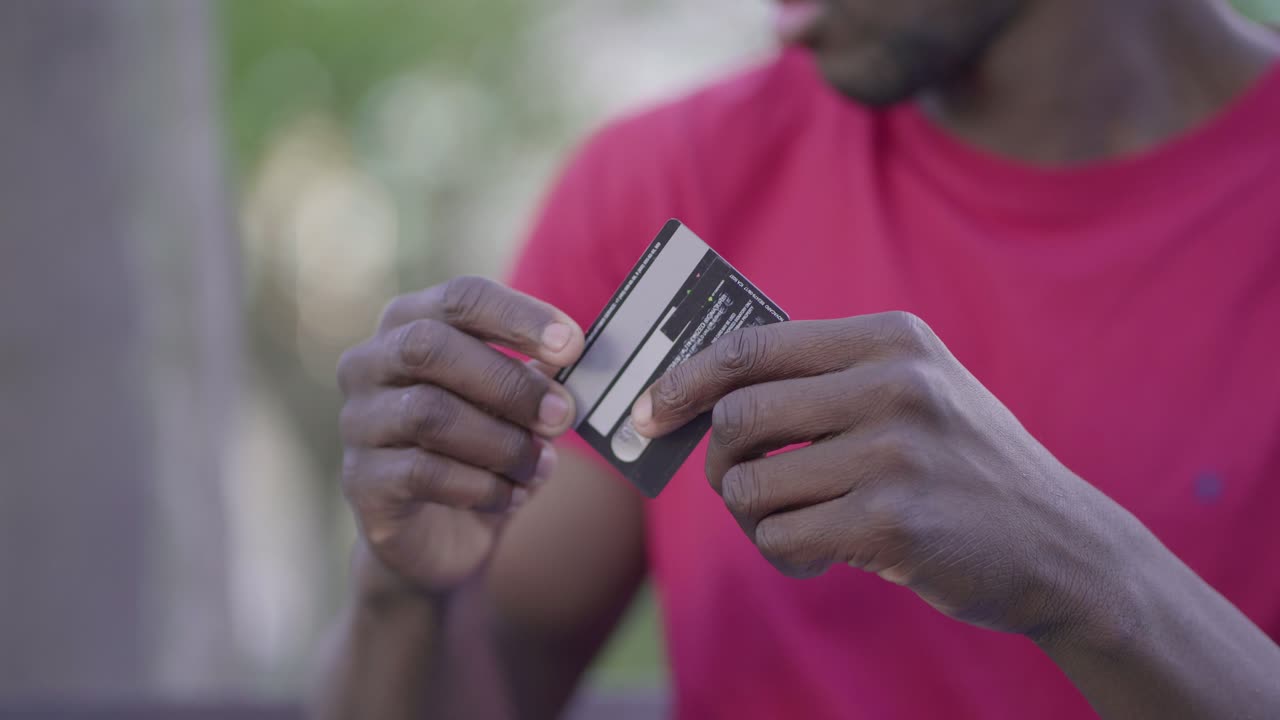 Closeup of male hands typing on laptop, paying with credit card