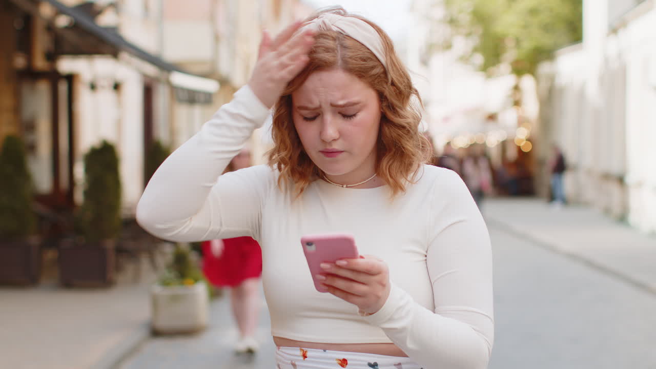 Woman using smartphone typing browsing loses bad news fortune loss fail fraud on urban city sunny
