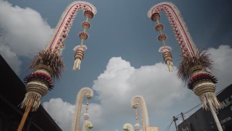 traditional balinese penjor decorations against a blue sky