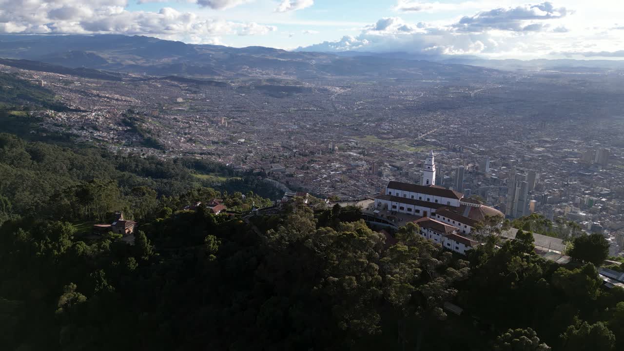 Drone view of Monserrate Sanctuary on mountain peak with Bogota city sprawling below - Colombia