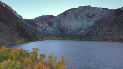convict lake canyon trail mammoth lakes mountain aerial drone california autumn fall later afternoon shaded rugged valley peaks yellow aspen birch trees clear skies sierra nevada range upwards motion