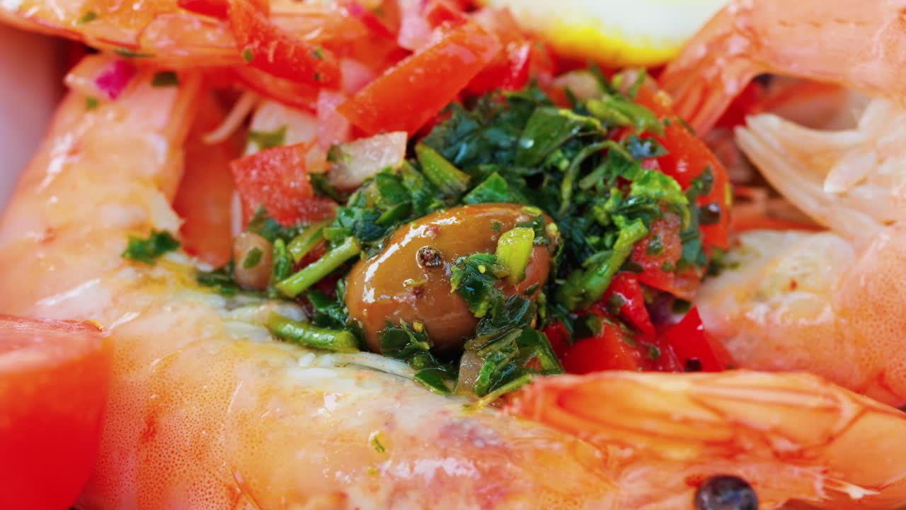 Close up of cooked shrimp with a slice of lemon and herbs on a white plate at a restaurant