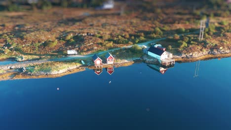 a serene aerial shot of red cabins by calm coastal waters