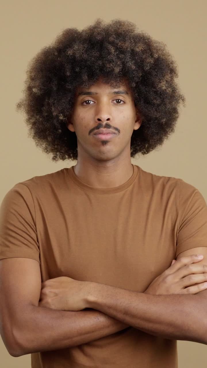 Portrait of a man with an afro and mustache, arms crossed