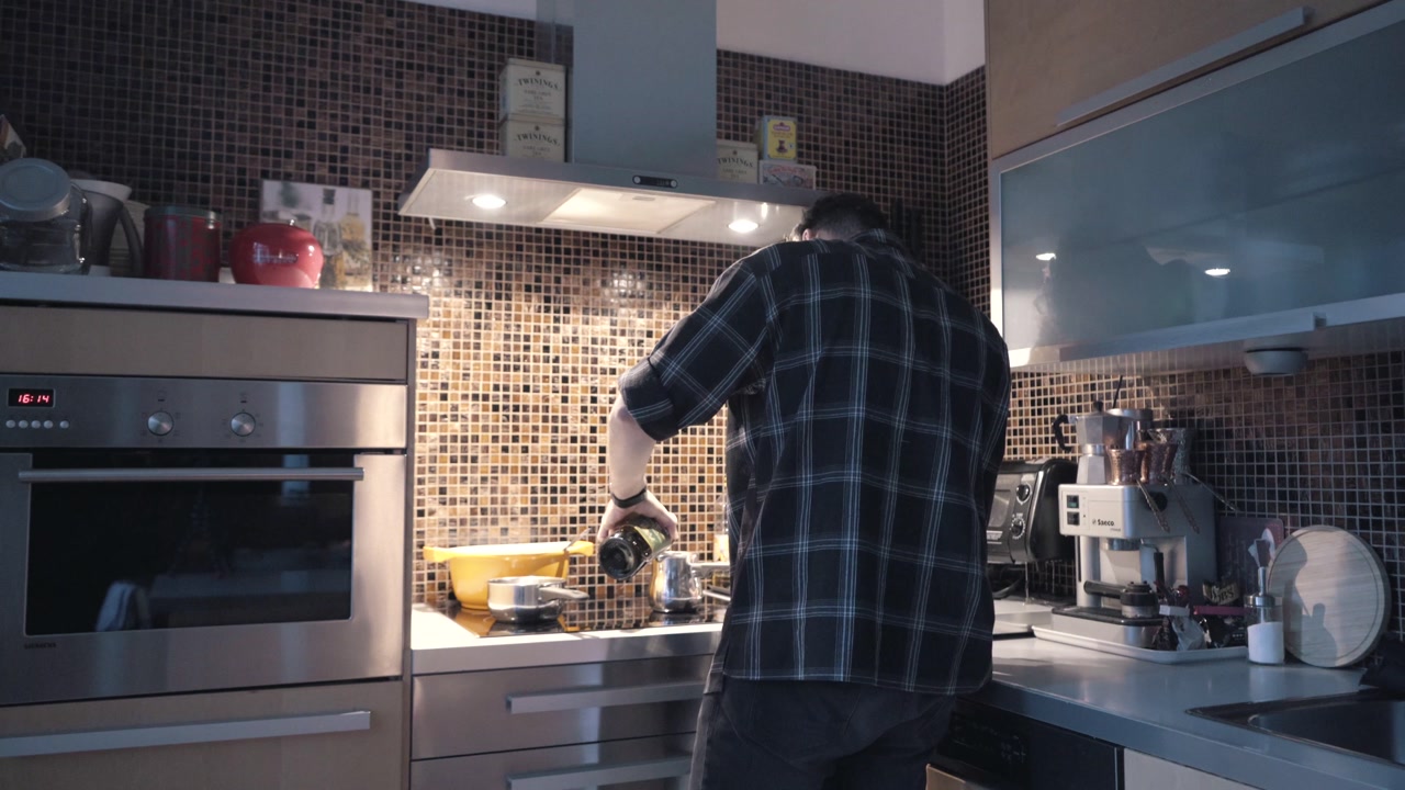 Man is preparing food and standing in the kitchen while waiting for the food to be done