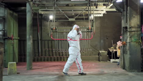 industrial metal coating. worker wearing protective wear performing powder coating of metal details