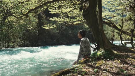 woman relaxing by a river in a forest