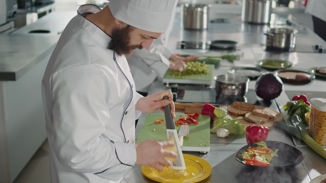 Male chef grating parmesan cheese on kitchen grater
