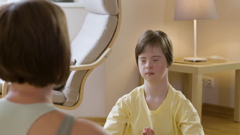 young girl practicing yoga with her mom at home and closing her eyes