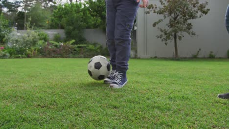 Caucasian-father-with-two-sons-playing-football-outdoors-in-garden