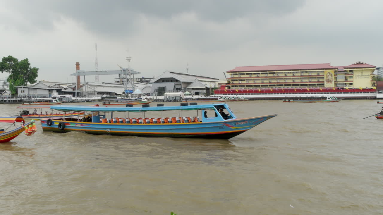 Passenger and tour boats cruising along the waters of Chao Phraya River in the city of Bangkok, Thailand.