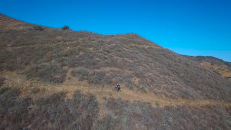 buena antena siguiendo a un ciclista de montaña ascendiendo una montaña de california