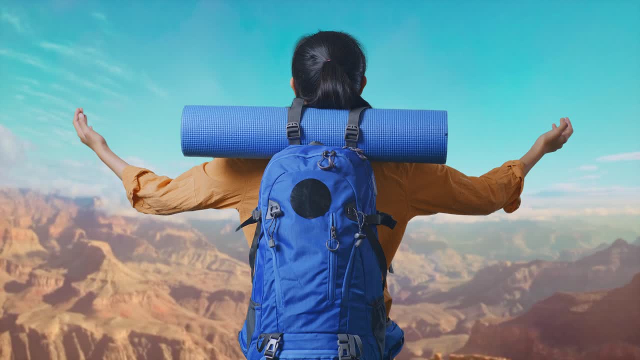 Back View Of A Female Hiker With Mountaineering Backpack Spreading Arms And Looking The View Around While Traveling At The Top Of Mountain