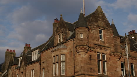 Red-stone-building-with-roof-and-windows-on-sunny-day-in-town