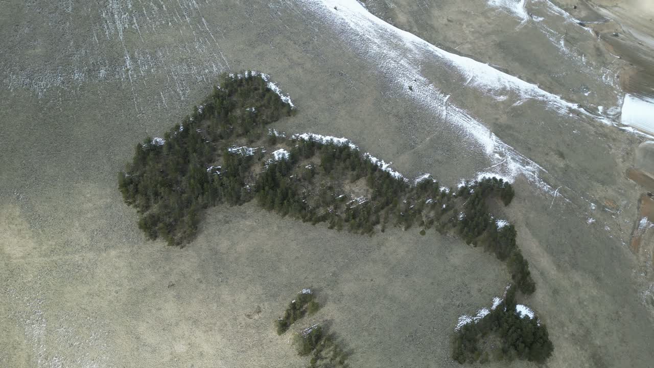 Aerial drone footage of Castelluccio di Norcia, Italy: winter landscape with snow on high peaks and green valleys below, clear sky and dramatic seasonal contrast. Ideal for travel and nature projects