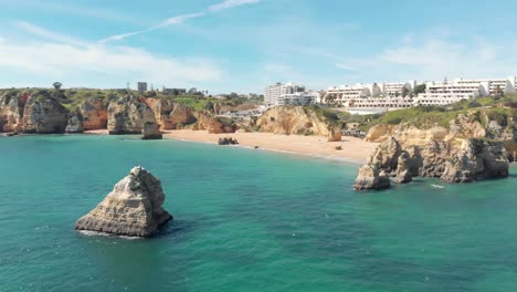 View-off-the-pristine-coastline-of-Dona-Ana-Beach-in-Lagos,-Algarve,-Portugal---Aerial-Wide-fly-back-shot