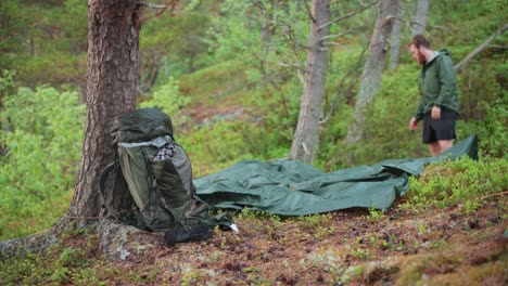 a male backpacker setting up a camping hammock in the forest