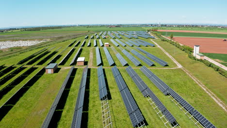 Una-Gran-Granja-Solar-Con-Hileras-De-Paneles-Solares-Bajo-Un-Cielo-Azul-Claro,-Vista-Aérea