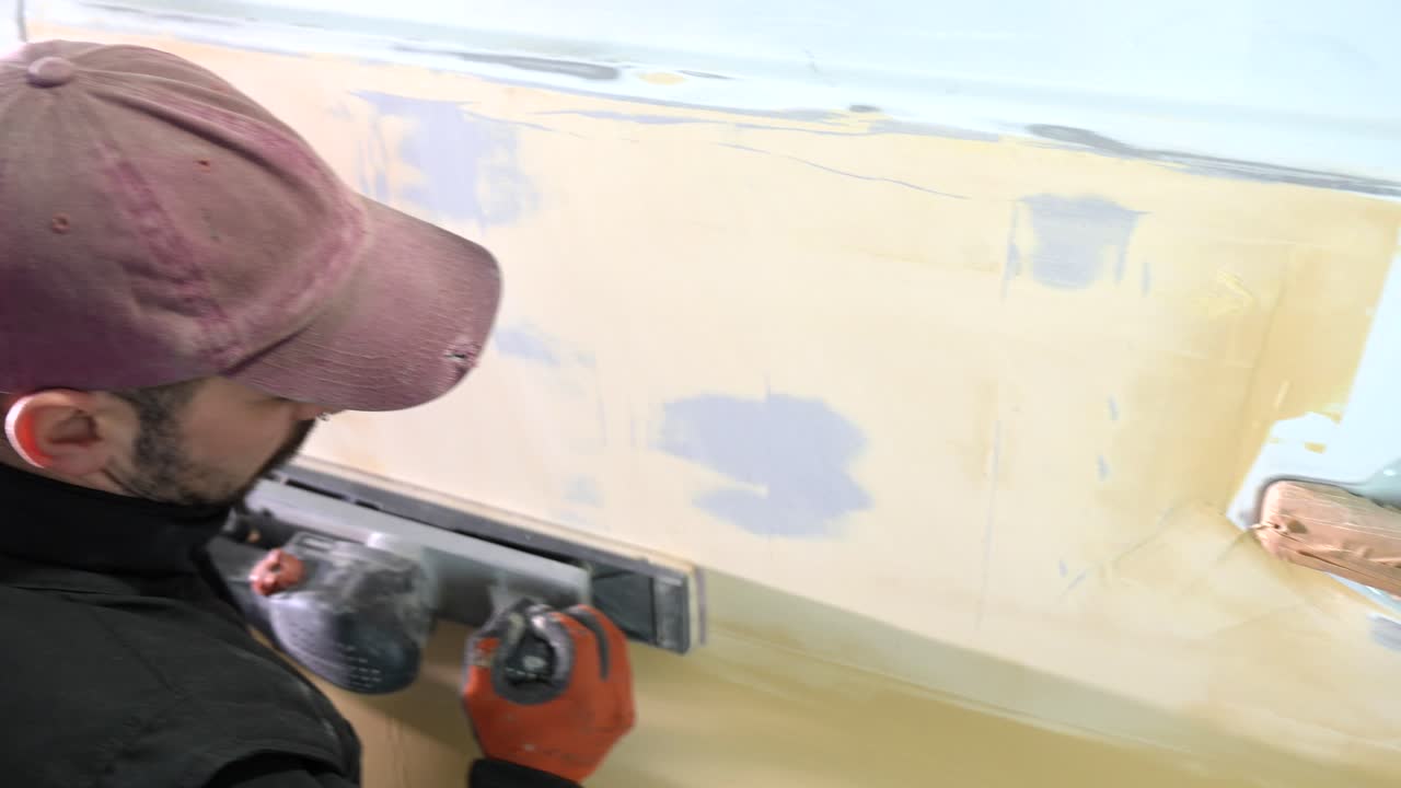 Man Sanding Car Body Panel in Auto Repair Workshop