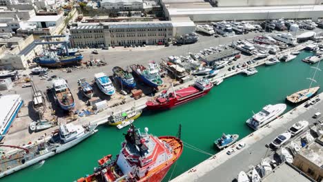 Aerial-orbit-drone-shot-around-several-ships-in-a-busy-boat-yard