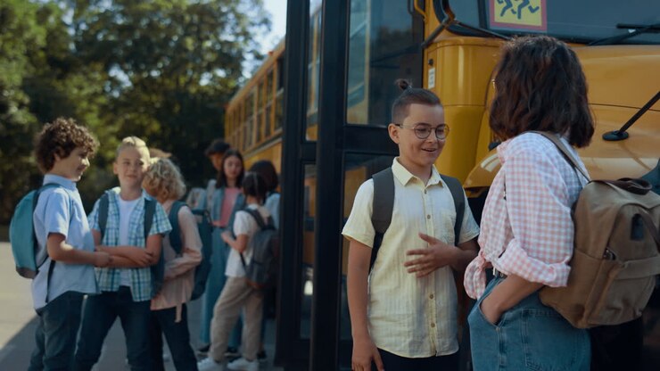 Students waiting schoolbus boarding. Pupils standing talking at yellow shuttle.