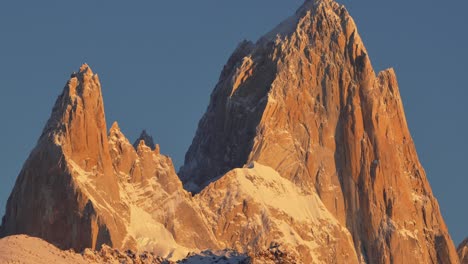 a plane passes in the distance as the sun sets over the snow-capped peaks of mount fitz roy