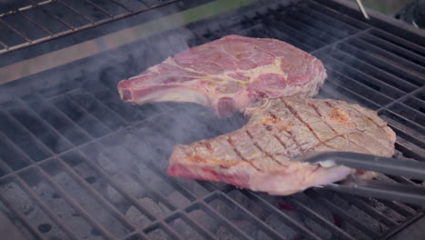 raw steaks grilling on a charcoal barbecue while seared on one side