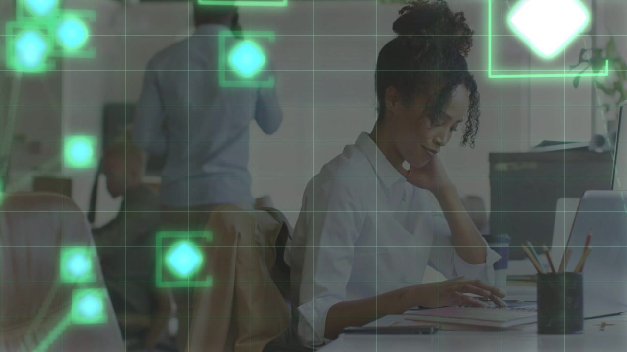Seated woman starting typing in office, activating green overlays drifting across laptop and papers