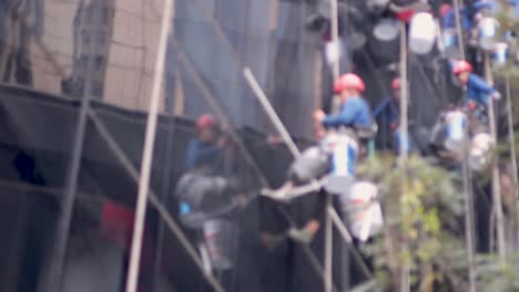 team of workers repairing windows on a tall building