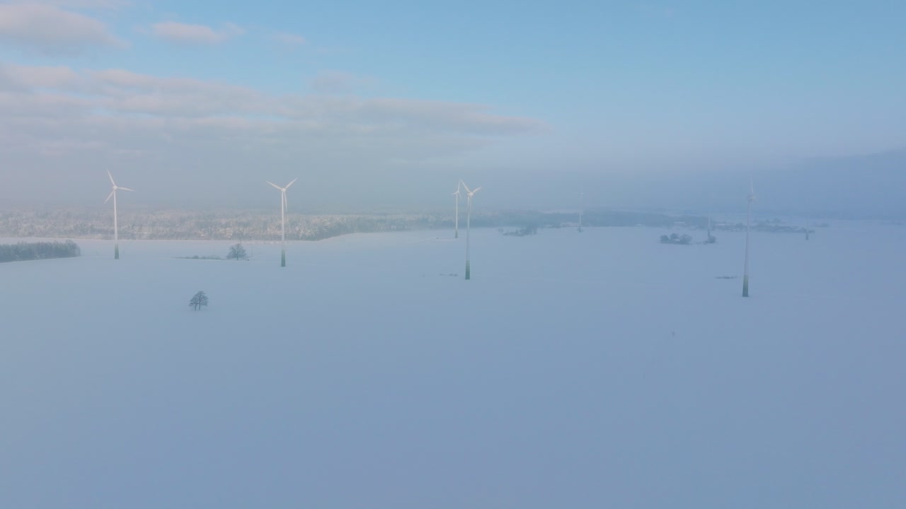 풍력 발전소에서 재생 에너지를 생성하는 풍력 터빈의 공중 전망 구축, 안개로 가득 찬 눈으로 가득 찬 시골 풍경, 화창한 겨울날, 넓은 드론 샷이 앞으로 이동