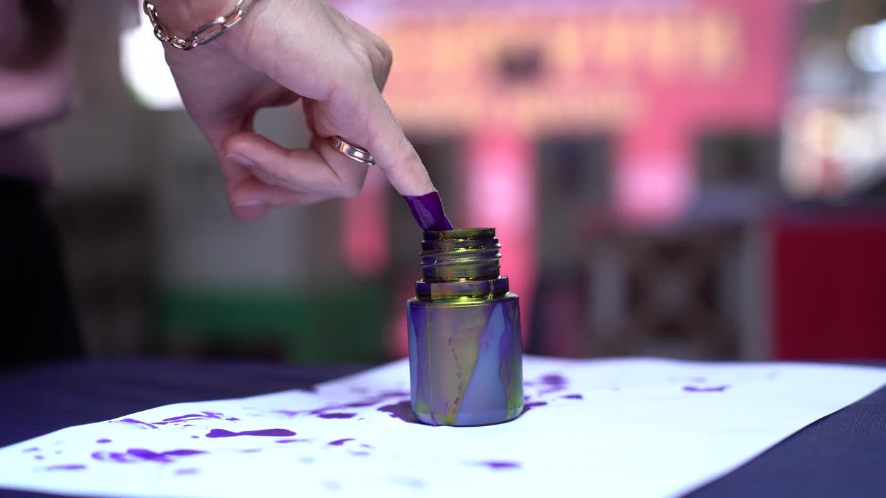 de cerca, sumergiendo el dedo meñique en tinta azul