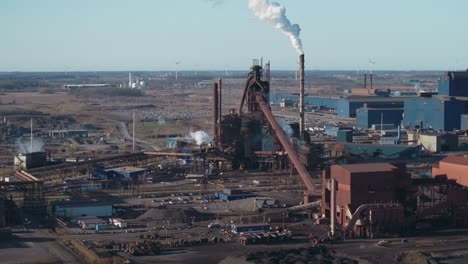 a busy industrial complex with smokestacks and structures, aerial view