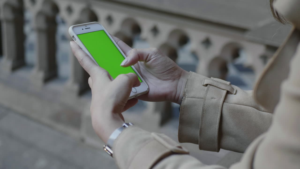 초록색 화면의 스마트폰을 사용하는 학생