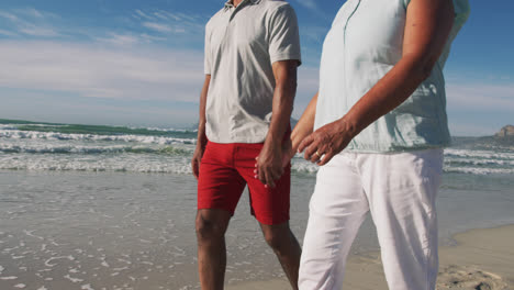 Senior-african-american-couple-walking-and-holding-hands-at-the-beach