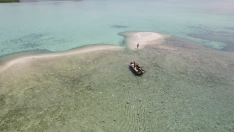 Pequeño-Grupo-De-Turistas-En-Barco-Acercándose-A-La-Isla-Desierta-De-Arena-Blanca-En-El-Parque-Nacional-De-Komodo,-Indonesia---Antena